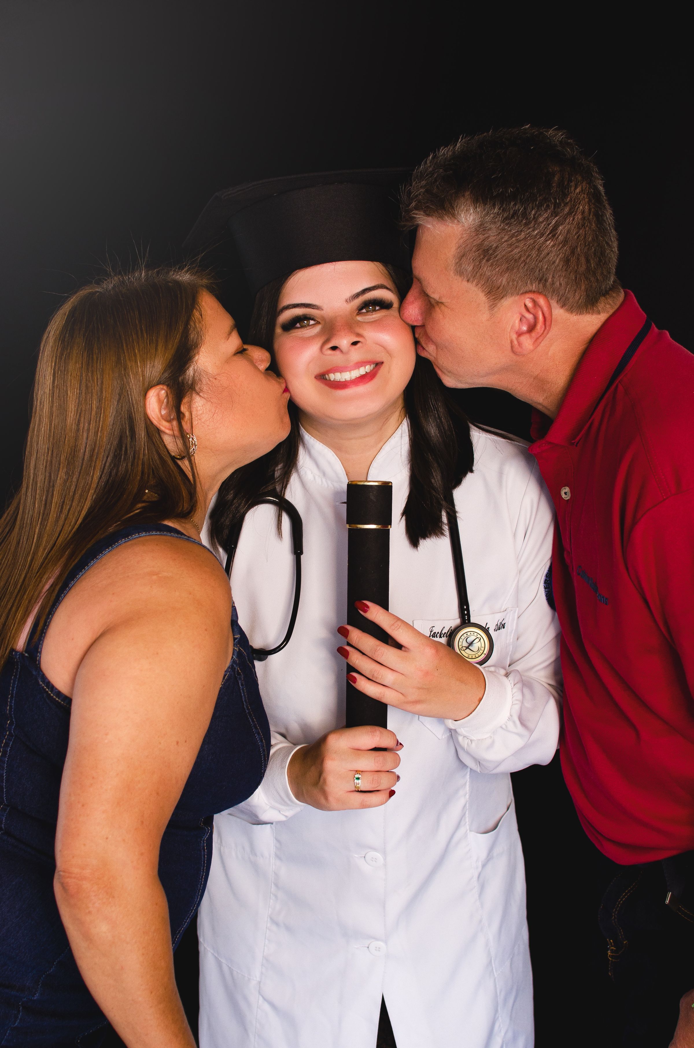 Doctor graduate being kissed by proud parents
