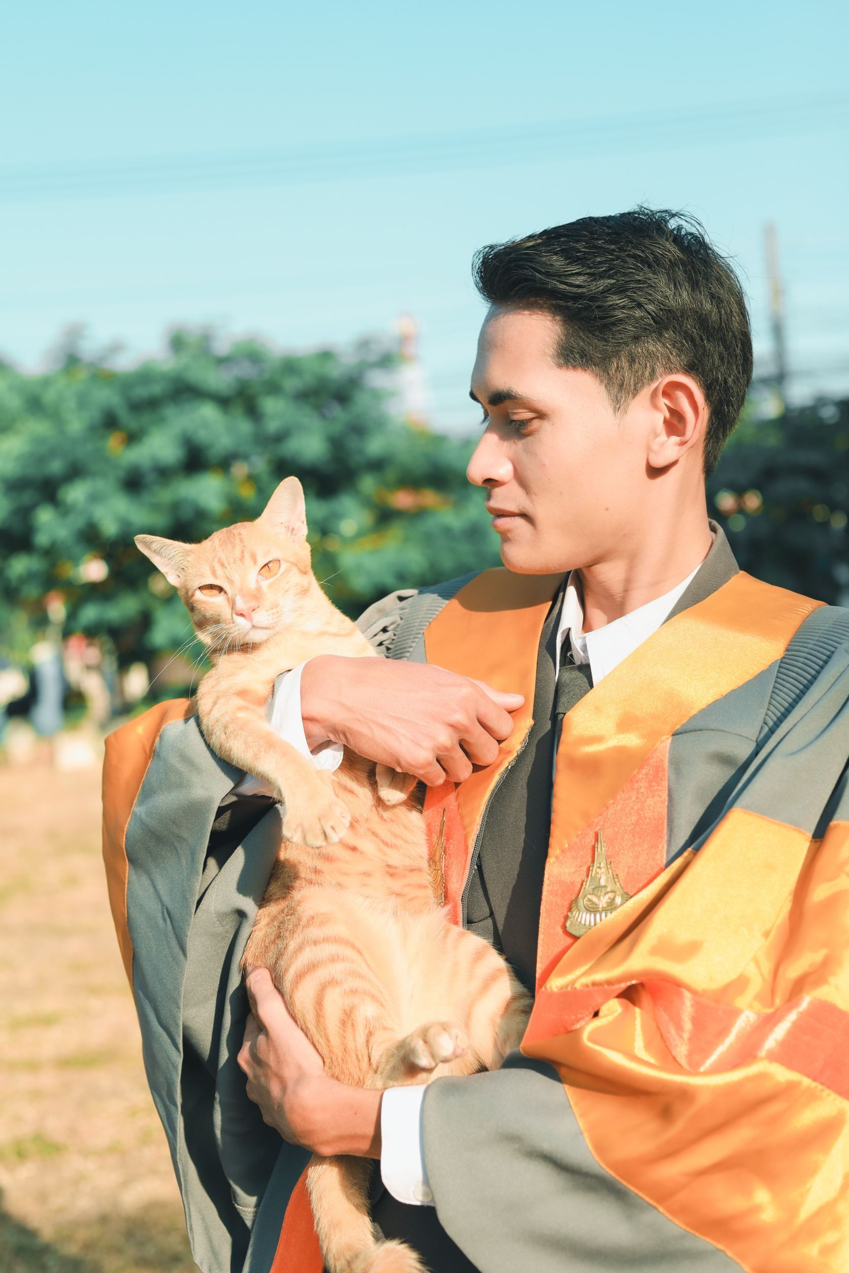 Graduate holding a cat at an outdoor ceremony
